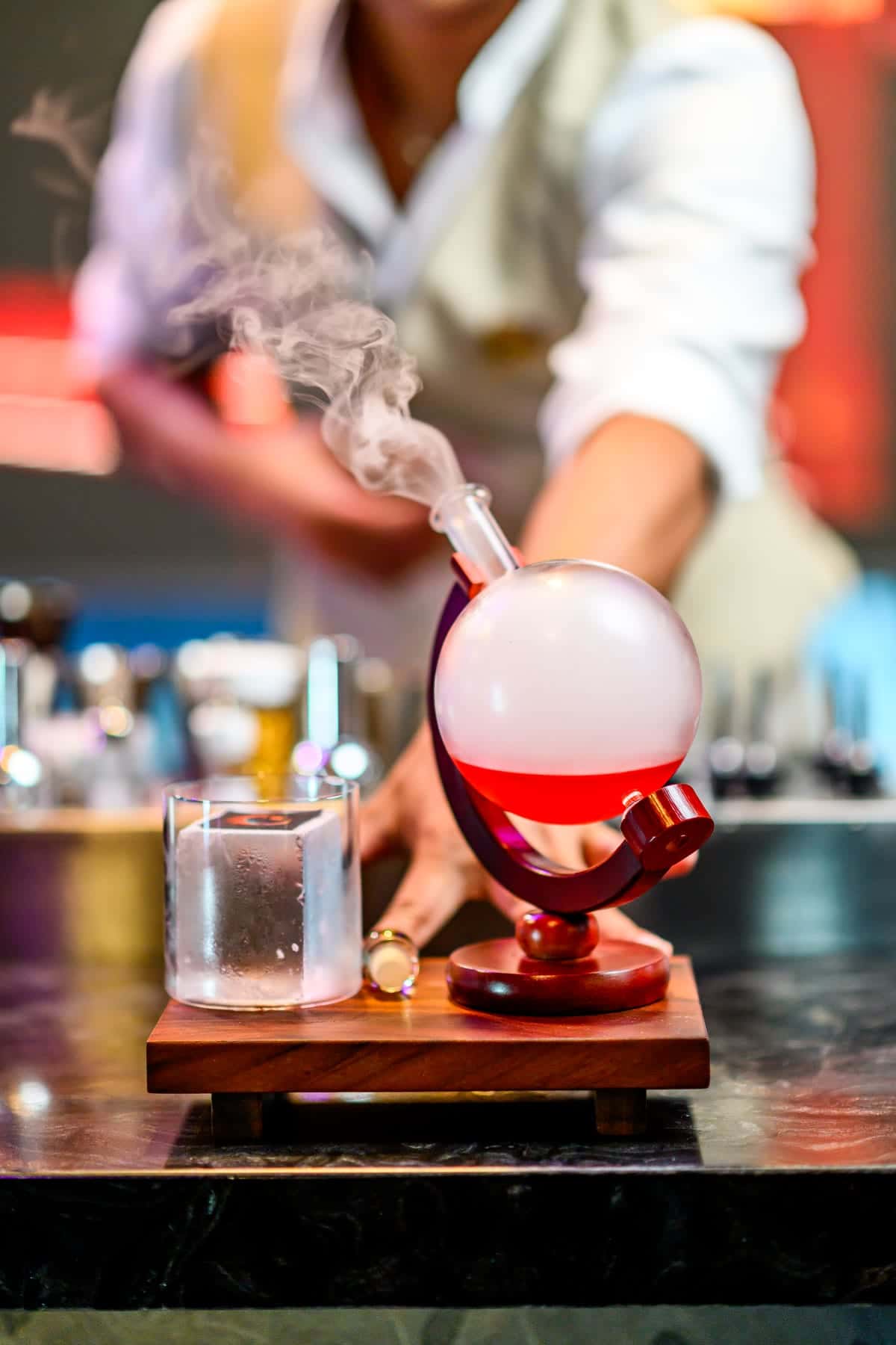 A globe decanter filled with smoke beside a chilled glass