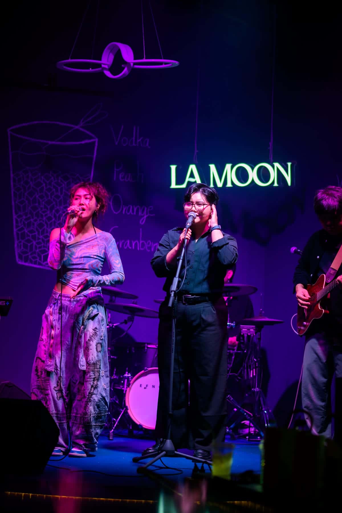 A band playing under the neon La Moon sign on the stage