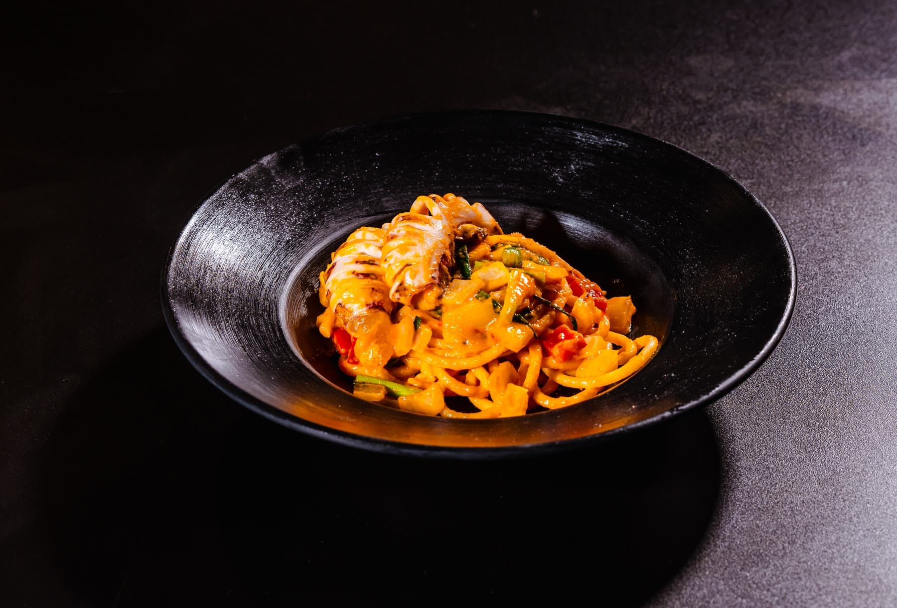 Squid spaghetti in salted egg sauce on a black plate